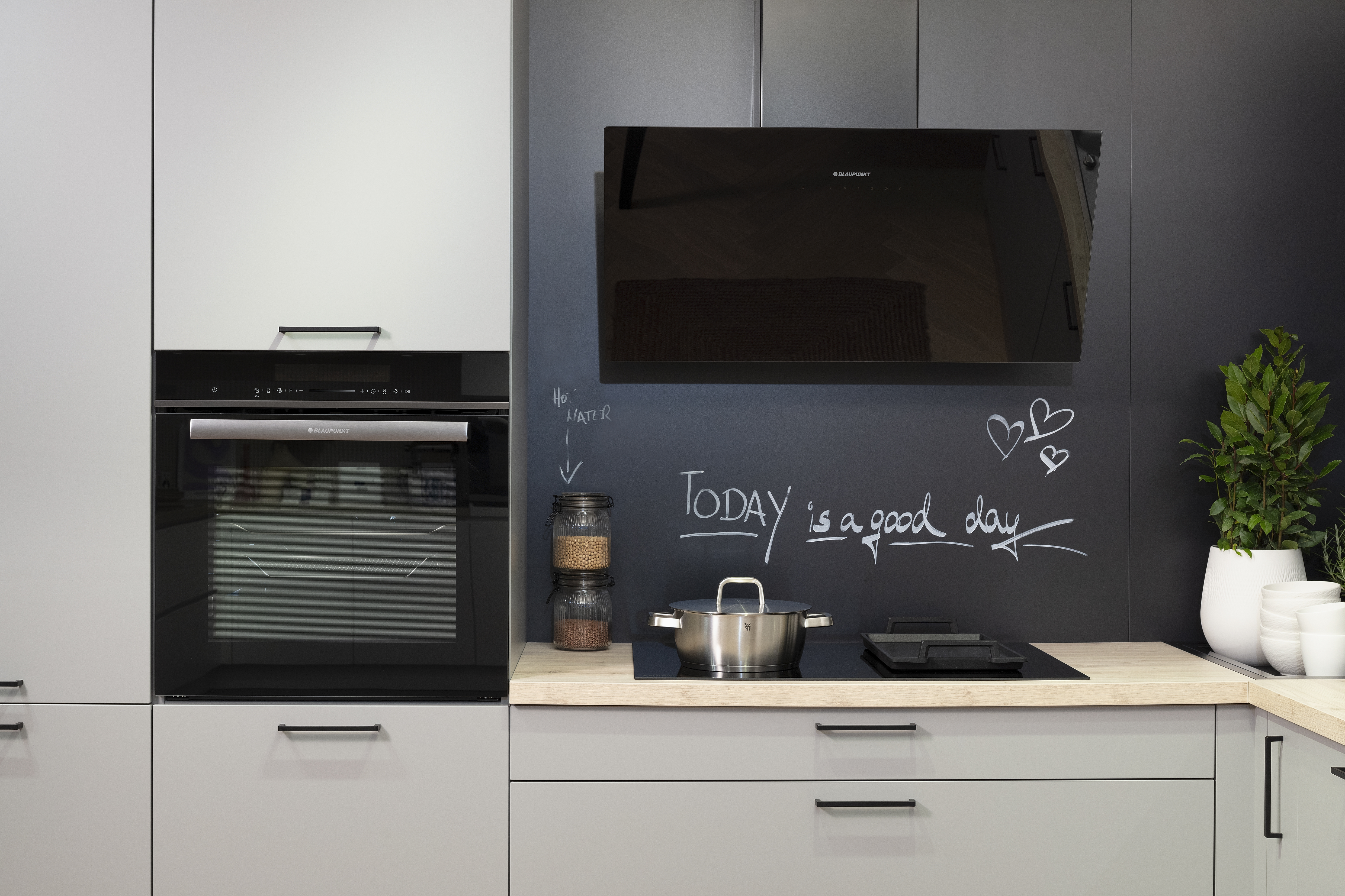 Häcker-Küche in Perlgrau mit Kochfeld, Backofen und Kopffreihaube von Blaupunkt. 