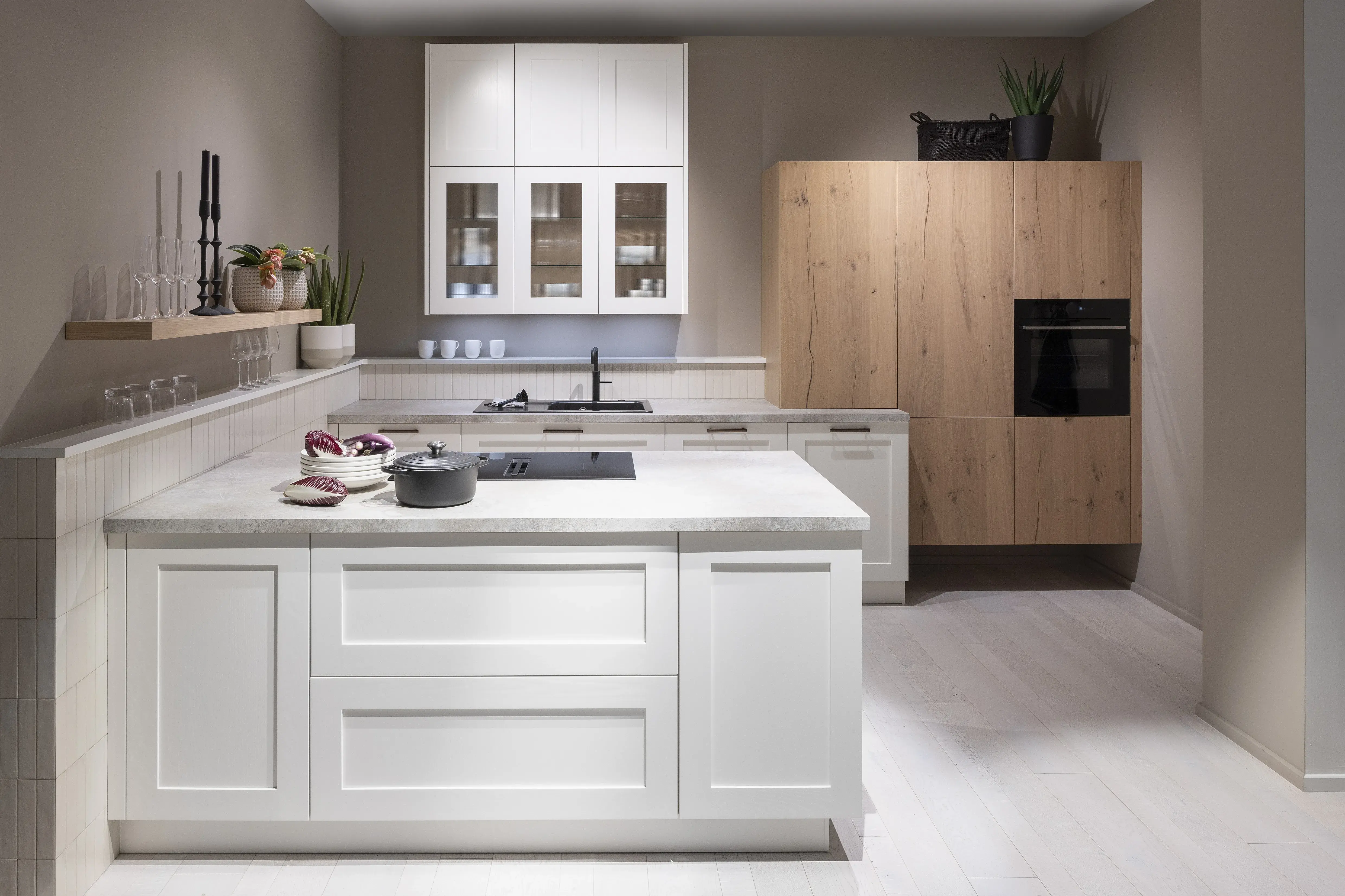 APL: 15 Kalkstein Repro 25 mm Front: AV 6055 Weiß Echtholz lackiert,  Front 2: AV 6082 Wildeiche-natur Korpus: 2085 Designkorpus Feineiche-natur Griff: 515 Metall Bronze-dunkel Geräte: Bosch  Armatur: Quooker Spüle: Systemceram   Features: Landhausküche modern, Echtholz RAL und NCS lackierbar, Riffelglasvitrine, Beleuchtung, schwebender Block, Echtholzfurnier lackiert kombiniert mit Echtholzfurnier, Fliesen, Korpus Echtholz Feineiche Natur, Griffe in Bronze. 